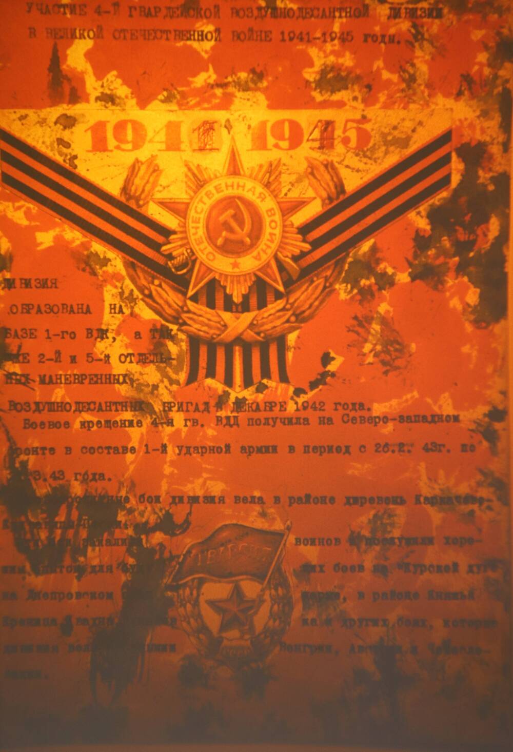 Слайд пластмассовый, где в набранном тексте показано участие 4-й воздушно-десантной дивизии в Великой Отечественной войне 1941-1945 годы. Фон слайда красный.