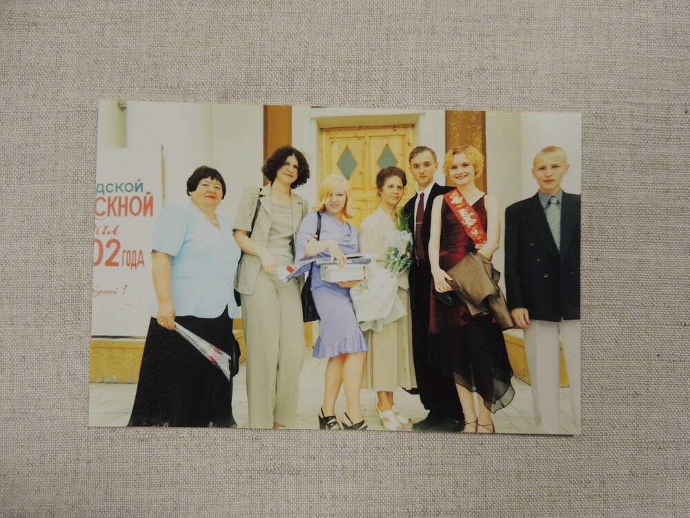 Фото цветные групповые Томышевой Н.Н. с коллегами, учениками, во время поздравления сотрудниками библиотеки, на сцене во время выступления ее ученицы и с выпускниками 2002 года на крыльце ДК Победа.