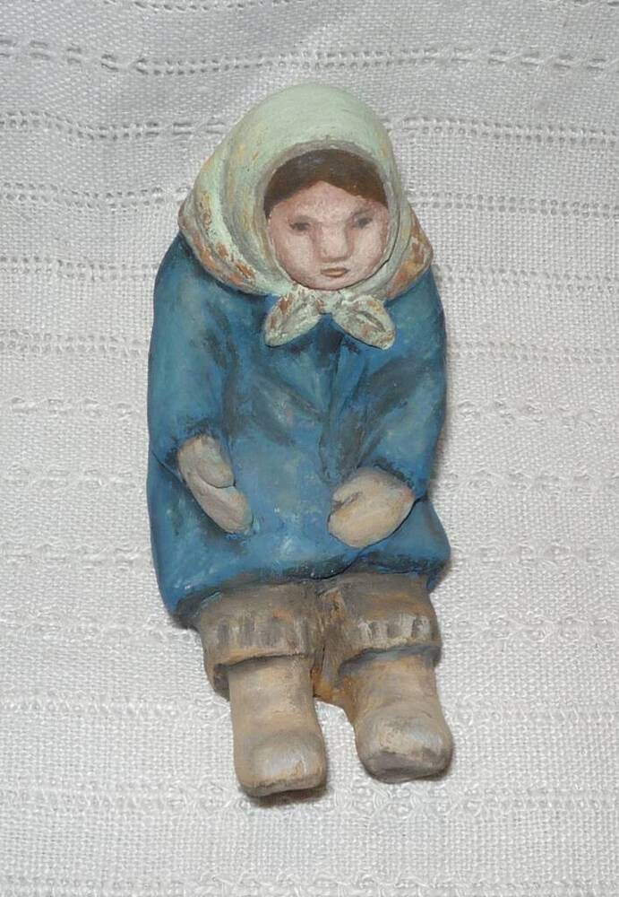 Скульптура. Сидящая девочка в синем пальто.