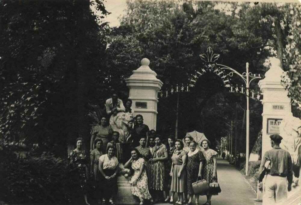 Фотография групповая. Группа людей запечатлены на фоне арки в честь 50-летия курорта Горячий Ключ со львами