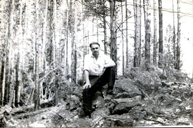 Фотография ч/б. Лапенков М. П. сидит на камне в лесу