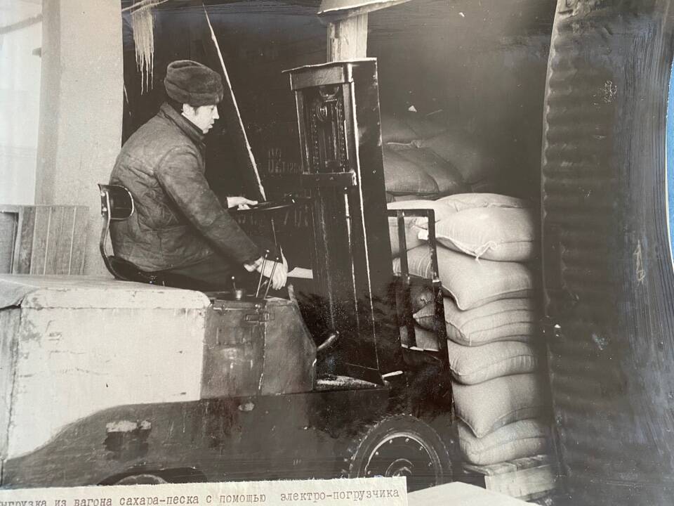 Фото чёрно-белое из альбома Механизация трудоёмких процессов в ОРСе в 1974 году. Выгрузка из вагона сахара-песка с помощью электропогрузчика и поддона.