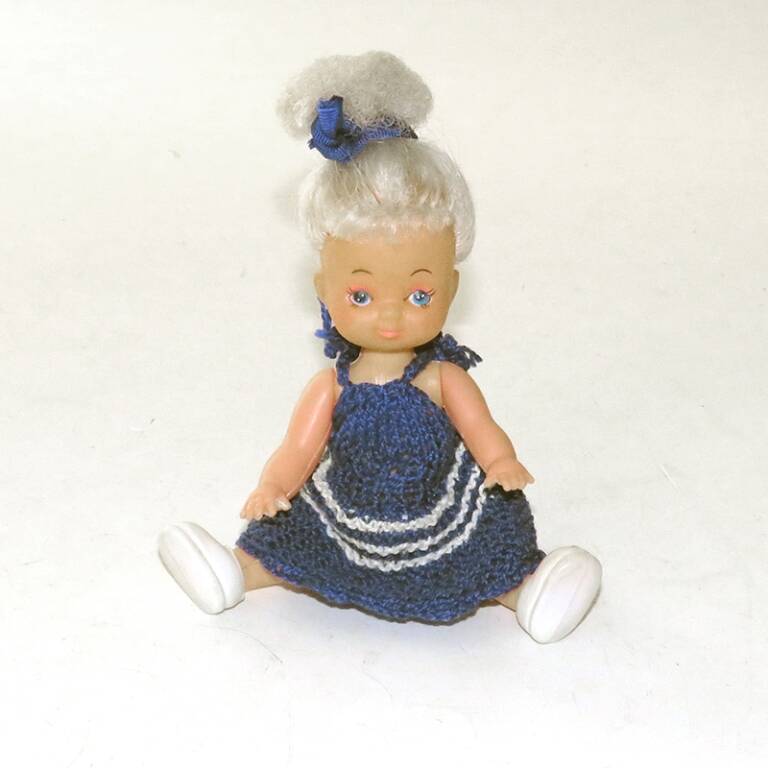 Кукла малая. С белыми прошивными волосами, собранными в пучок синей тесьмой, в вязаном синем с 3 белыми полосами сарафане, на ногах башмаки. Китай, 1990-е г.