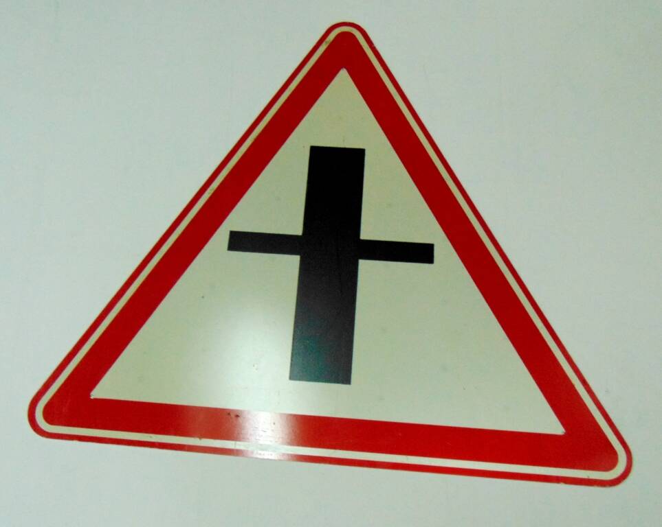 Дорожный знак в виде белого треугольника с красной каймой и изображением двух пересекающихся черных линий - знак приоритета Пересечение со второстепенной дорогой. 1996 г.