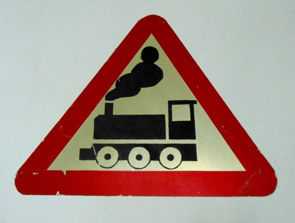 Дорожный знак в виде белого треугольника с красной каймой и изображением паровоза - предупреждающий знак Железнодорожный переезд без шлагбаума. 1996 г.