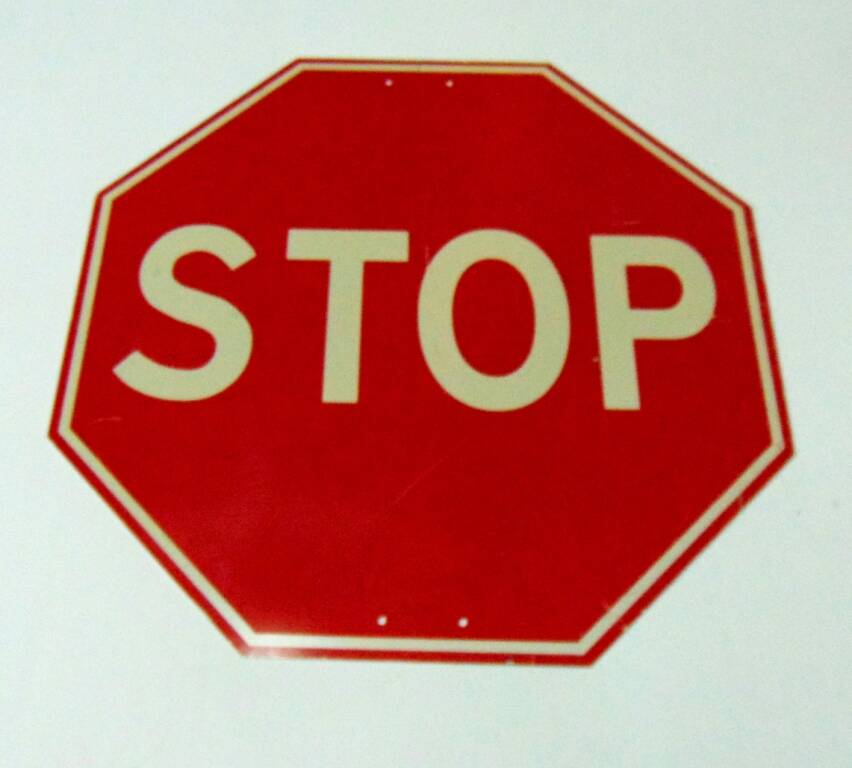 Дорожный знак в виде восьмигранника красного цвета с белой надписью латинским шрифтом Stop - знак приоритета Движение без остановки запрещено. 1996 г.