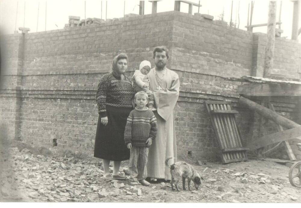 Фотография черно-белая. Г.М. Самойленко с женой и детьми на строительстве нового храма. На заднем плане кирпичная стена западной части строения.