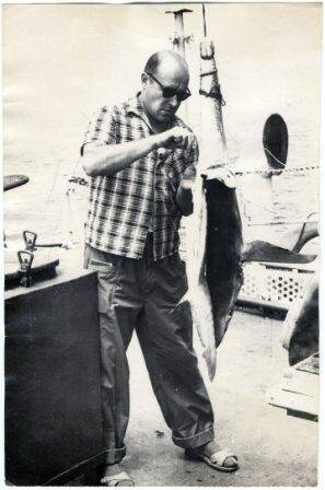 Фотография. Фото сюжетное. А.И. Флеров на палубе китобойной базы снимает шкуру с подвешенной за хвост акулы. 1971 г.