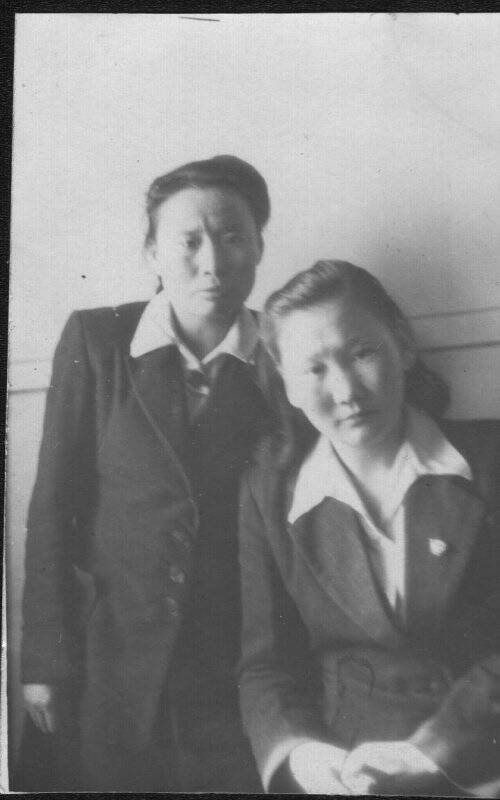 Фотография черно-белая. Двое: стоит Охлопкова М.А., рядом сидит подруга. 1952 г.