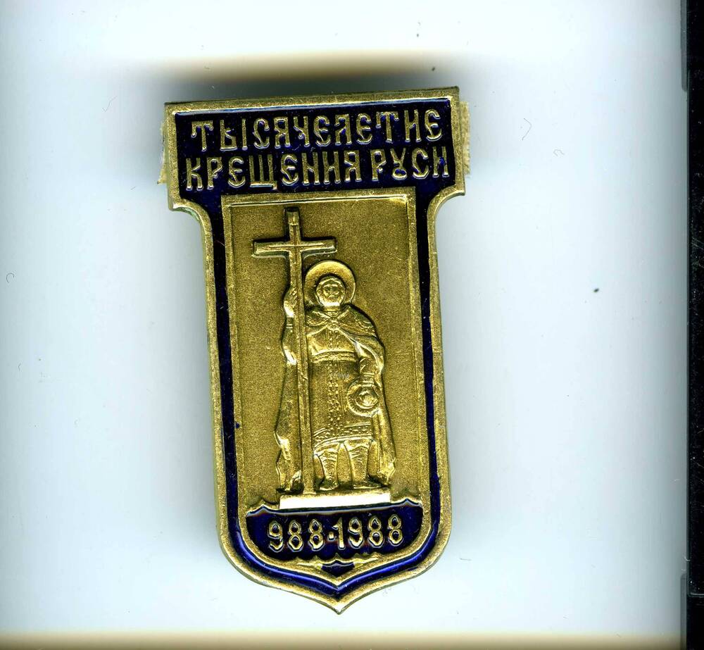 Значок прямоугольной формы, с выступом в верхней части и закругленный внизу, с изображением св.Владимира и надписью Тысячелетие крещения Руси 988-1988.