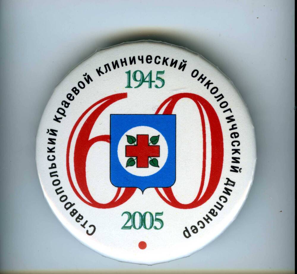Значок круглый белого цвета с надписью:Ставропольский клинический онкологический диспансер, сверху и снизу даты:1945-2005 гг., посредине цифра 60 и красный крест.
