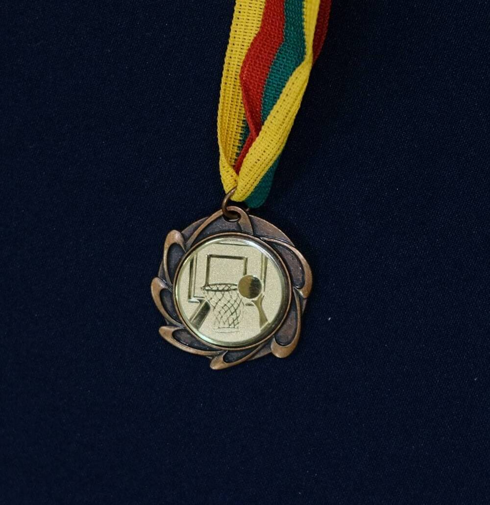 Медаль Oz pergales siekima-круглой формы с изображением баскетбольной корзины и мяча.