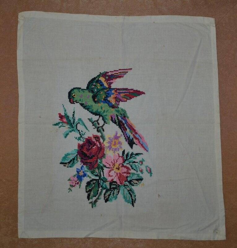 Салфетка белого цвета с вышивкой крестом. Изображен цветочный мотив и попугай.