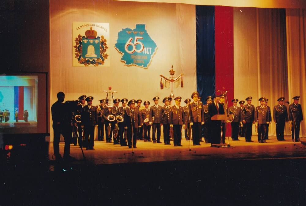 Фото цветное групповое: торжественное собрание в честь 65-летия со дня образования Тамбовской области. Выступает губернатор Бетин О. И., на заднем плане военный оркестр