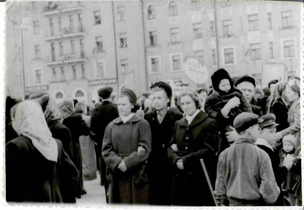 Фотография. В черно-белом цвете. Фигурная обрезка по краям. Люди на городской площади на фоне здания времен сталинской постройки, 1950-е гг.