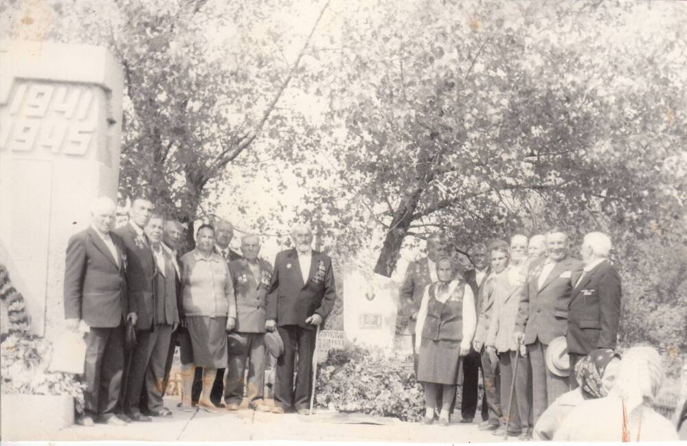 Фотография черно-белая. Группа ветеранов стоят у памятника героям, павшим в годы Великой Отечественной войны 1941-1945 гг.