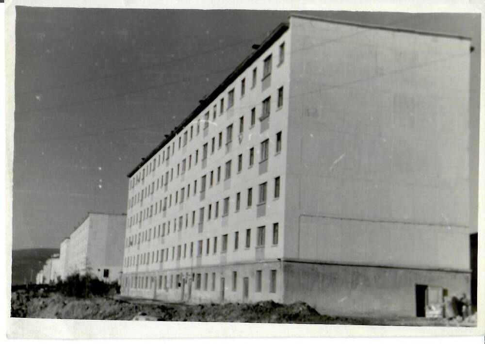 Фотография черно-белая, глянцевая печать. На фото: вид на пятиэтажные дома вдоль улицы.  г. Магадан, 1966 г.