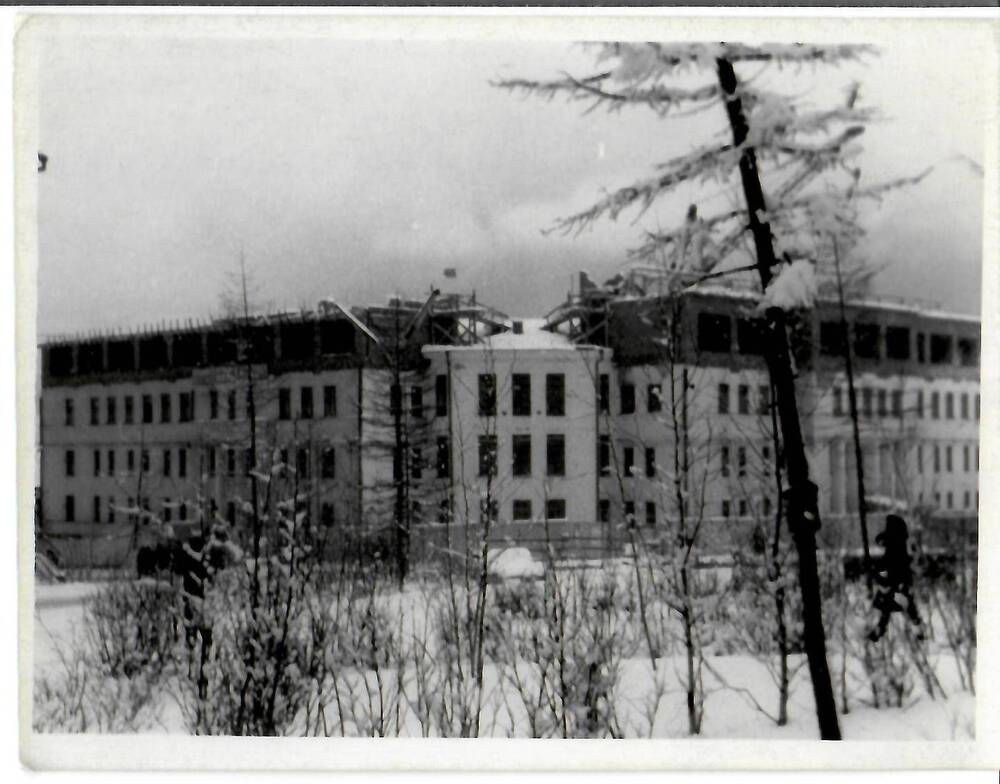 Фотография черно-белая, глянцевая печать. На фото: вид на трехэтажное здание в процессе надстройки четвертого этажа зимой. На обороте машинописный текст: «Снег в Магадане – 24.У.66г.», г. Магадан, 1966 г.