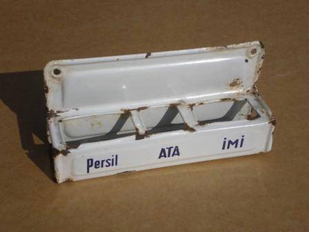 Полочка настенная под упаковки с моющими средствами, белого цвета. Имеются надписи синими буквами на лицевой стороне - Persil  ATA  IMI.
