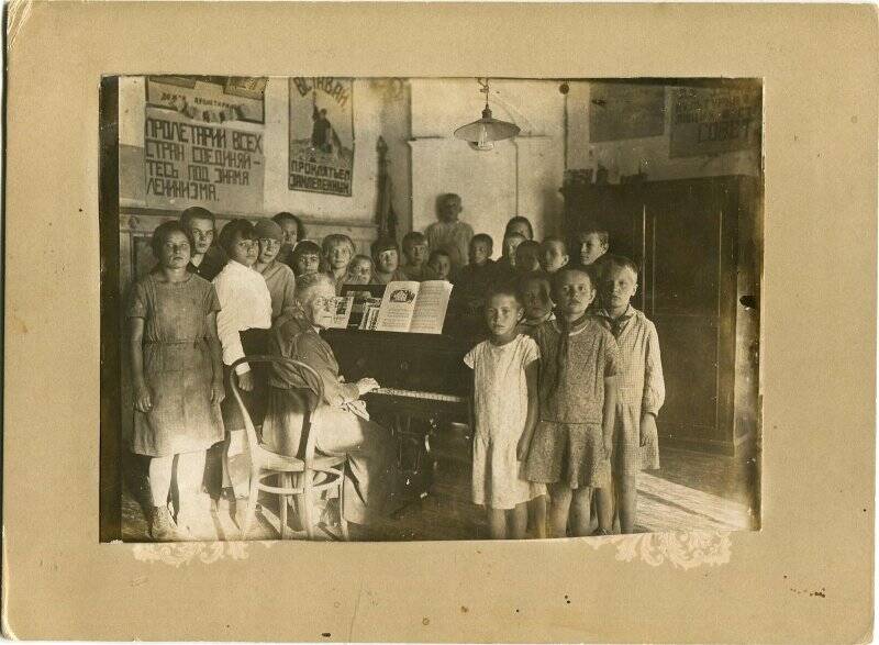 Фотография ч/б. Фото групповое. Урок музыки. За роялем преподаватель музыки М.В. Попова- Веденская. 1.09.1932 г. Фото наклеено на картон.