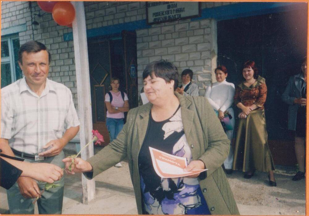 Фотография цветная сюжетная. Вручение грамоты учителю Калиновской школы Осиповой Т.Н. возле здания школы.