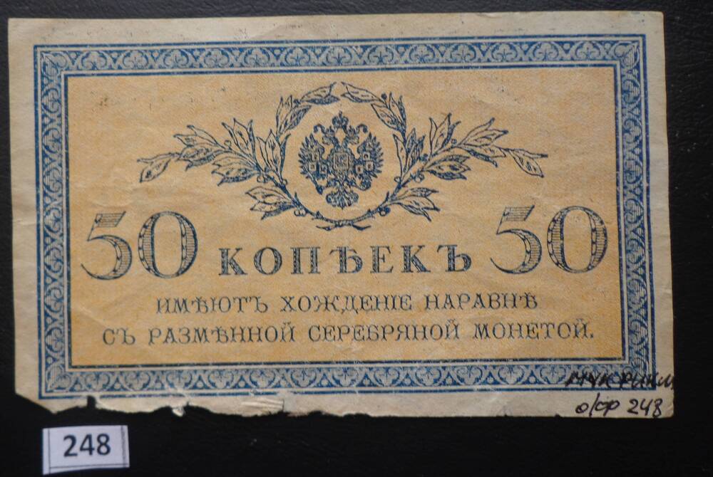 Денежный знак 50 копеек имеет хождение наравне с серебряной монетой, купюра жёлтого цвета с синей рамкой и изображением российского герба.