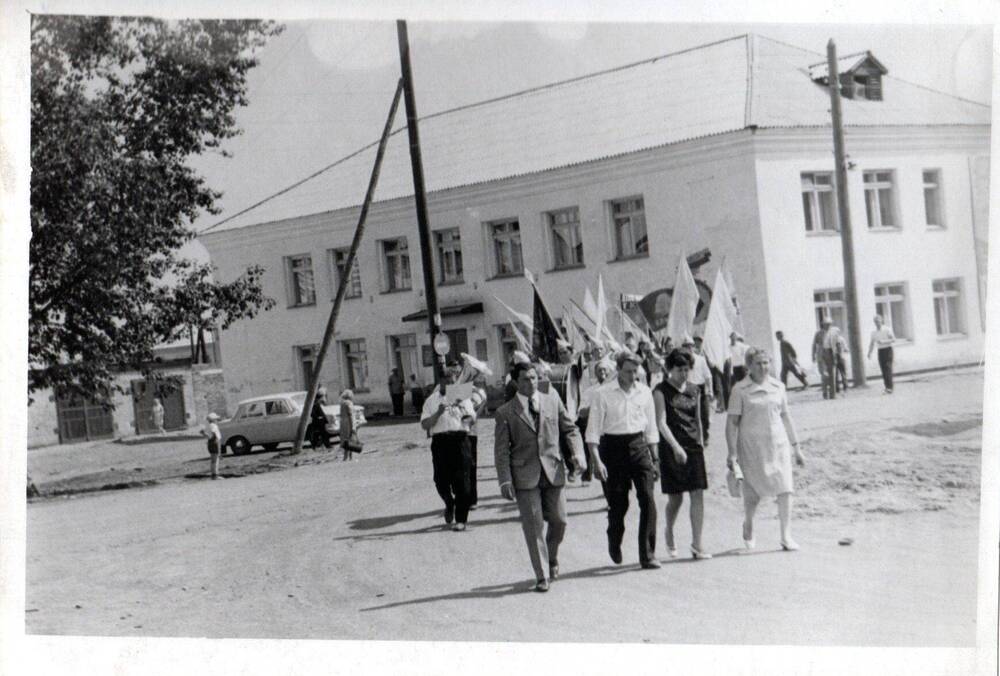 Фотография ч/б колонны сотрудников Тисульского РК КПСС.
 п. Тисуль. 70-е годы ХХ века.