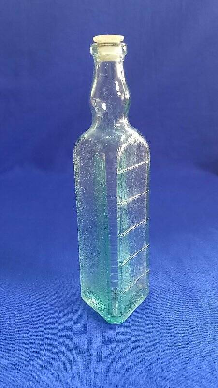Бутылочка из–под уксуса из прозрачного стекла, светло – зеленого цвета, трехгранная. Поверхность бутылки ребристая с двух сторон.