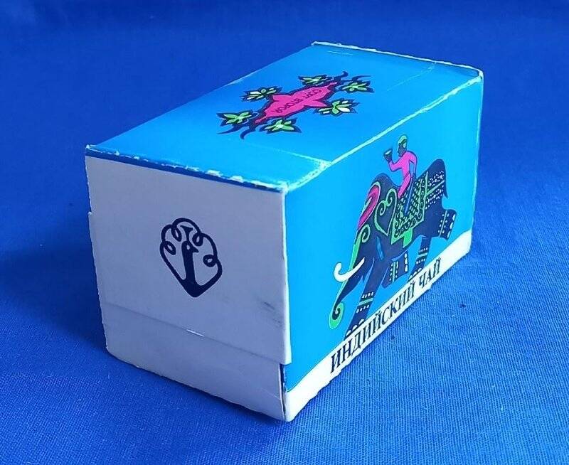 Коробка чайная «Индийский чай» картонная, разноцветная, запечатанная, чай упакован внутри. Коробка объемная - многогранник с с шестью гранями. На синих сторонах коробки  с двух сторон изображен слон с опущенным хоботом, идет влево, на слоне сидит погонщик. На оборотной белой стороне напечатано: «ГОСАГРОПРОМ нечерноземной зоны РСФСР Серпуховский завод пищевых концентратов чай черный байховый мелкий МАССА НЕТТО 125 г Цена 75 коп. ТУ 10-04-05-28-88». СССР.