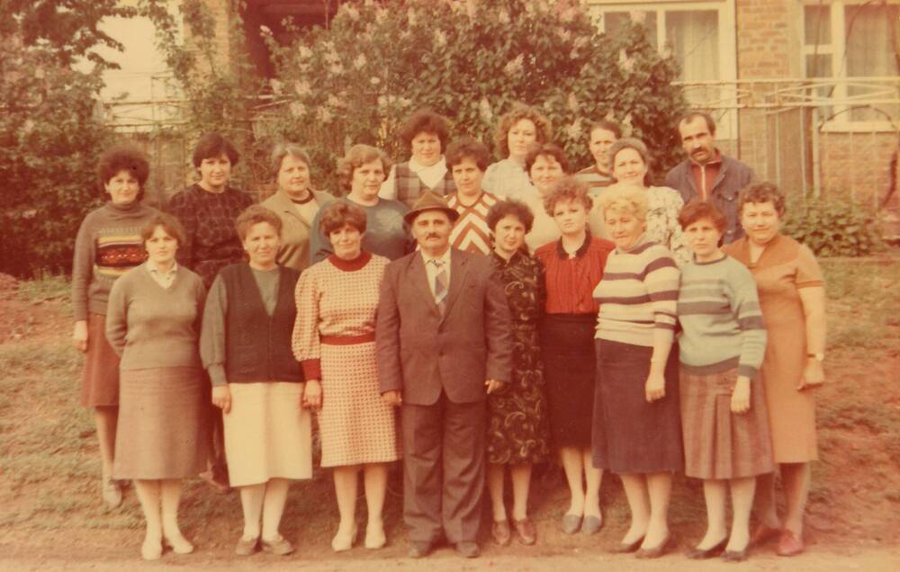 Фотография. Директор Куршубадзе А.Х. (в центре) с коллективом на фоне на фоне куста цветущей сирени.