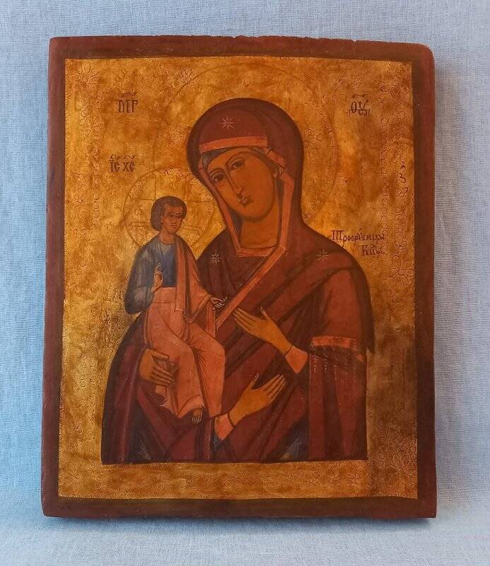 Икона Богоматери «Троеручица». На иконе изображена Богородица с младенцем на руках. Фон неравномерный, пятнами, золотистых и серебристых оттенков.