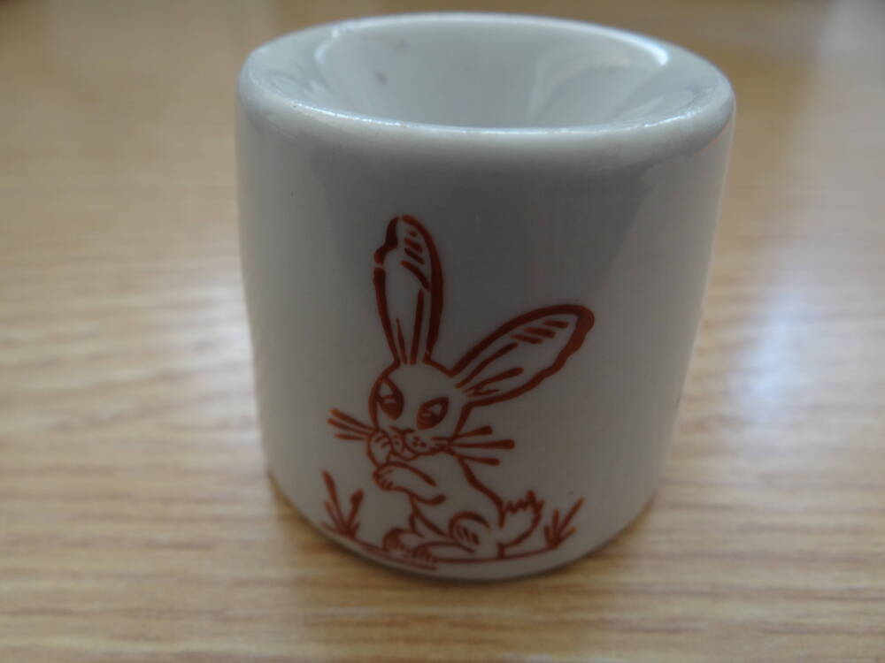 Чернильница-непроливайка белого цвета, керамическая, с рисунком зайца, выполненным коричневым цветом. На дне непроливайки чернильницы стоит клеймо в виде чайной чашки 1с