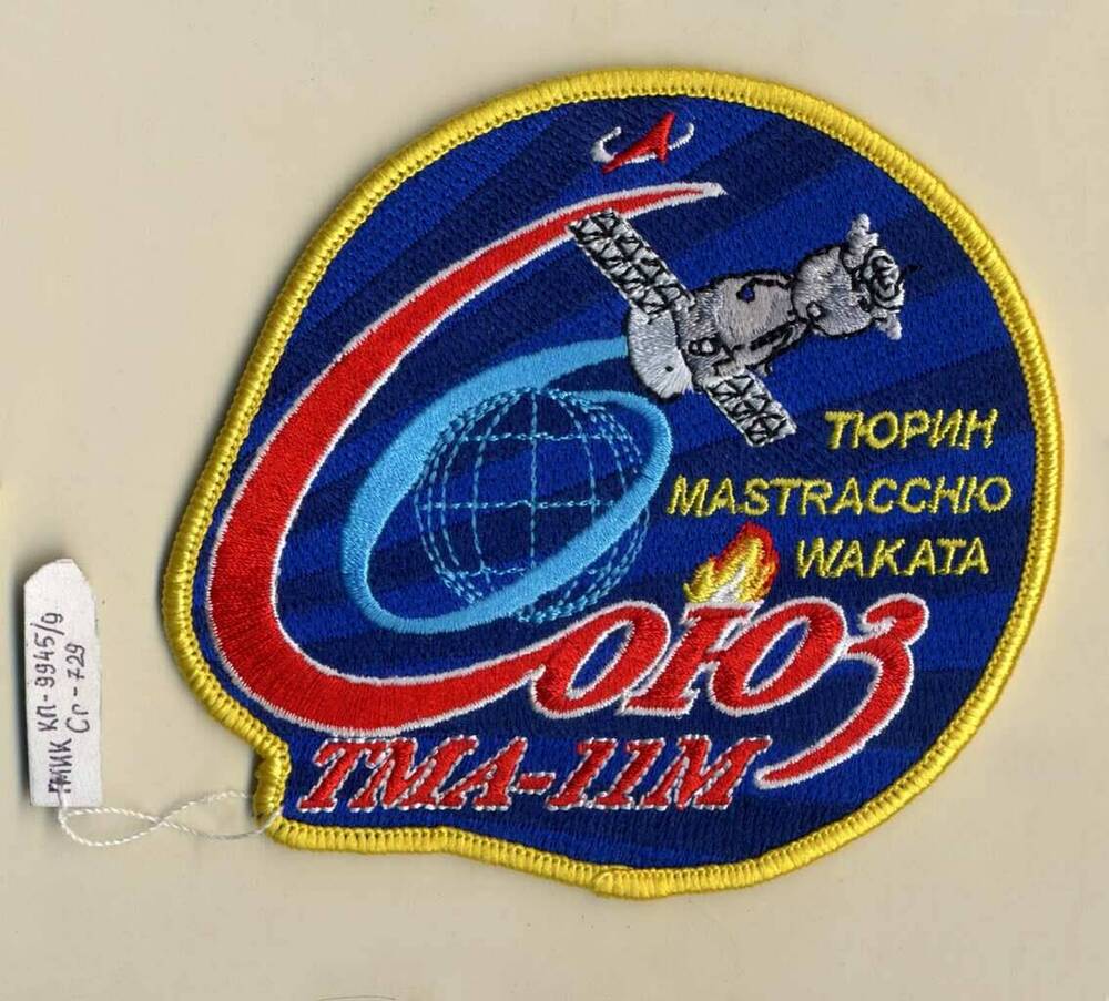 Эмблема полетная экипажа космического корабля «Союз ТМА-11 М» в составе космонавтов М. Тюрина (Россия), астронавтам Р. Мастраккио (США), К. Ваката (Япония)