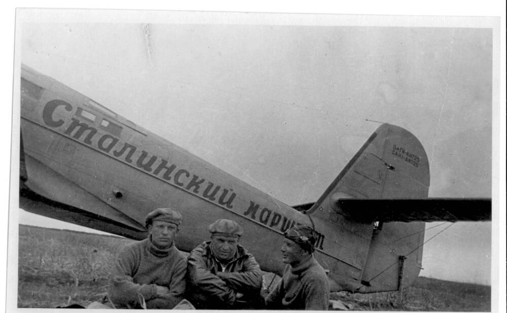 Фото. Экипаж самолета АНТ-25 В. П. Чкалов, Г. Ф. Байдуков  А. В. Беляков сидят  у самолета на о. Удд.