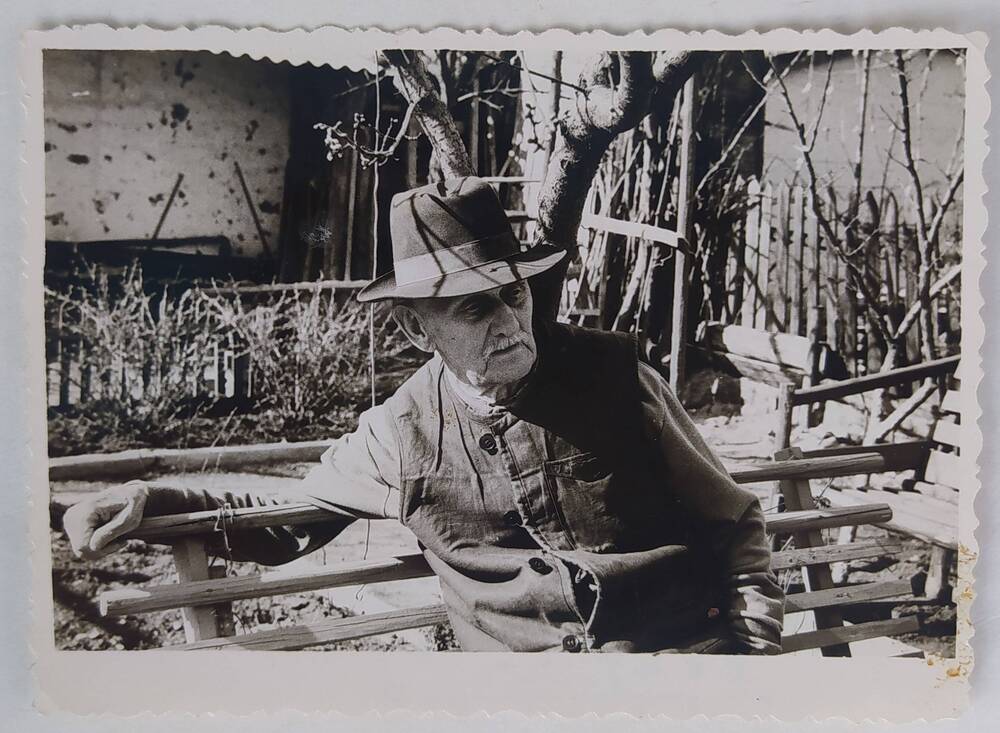 Фотография черно-белая глянцевая погрудная. А.П. Бибик сидит на лавочке в весеннем саду.