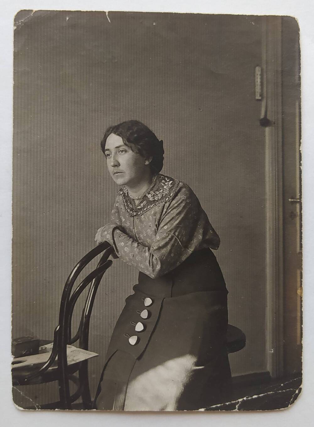 Фотография черно-белая с изображением жены А.П. Бибика - З.И. Бибик, которая сидит на табурете, облокотившись на спинку венского стула.