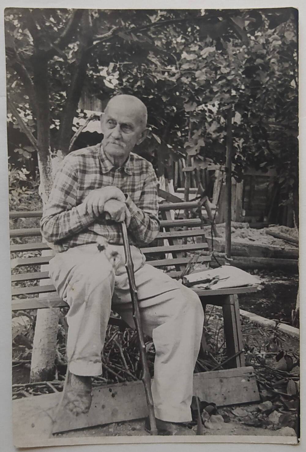 Фотография черно-белая. А.П. Бибик сидит на лавочке на улице.