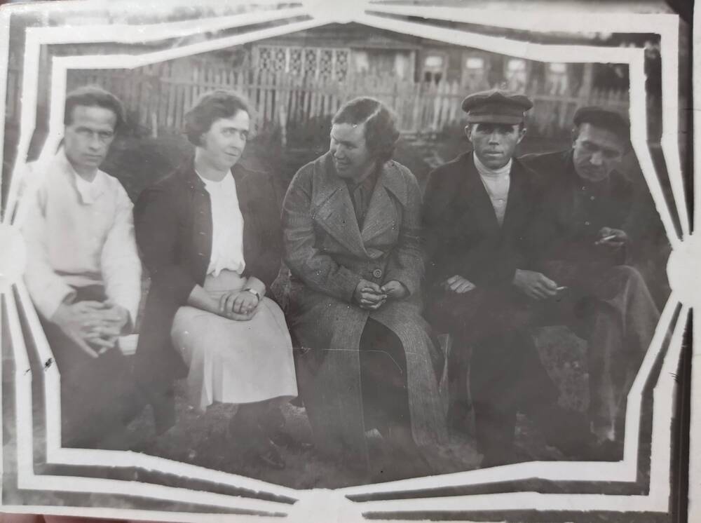 Фотография. О.Э.Чкалова на родине В.П.Чкалова сидит на горке около дома на скамеечке с его земляками.