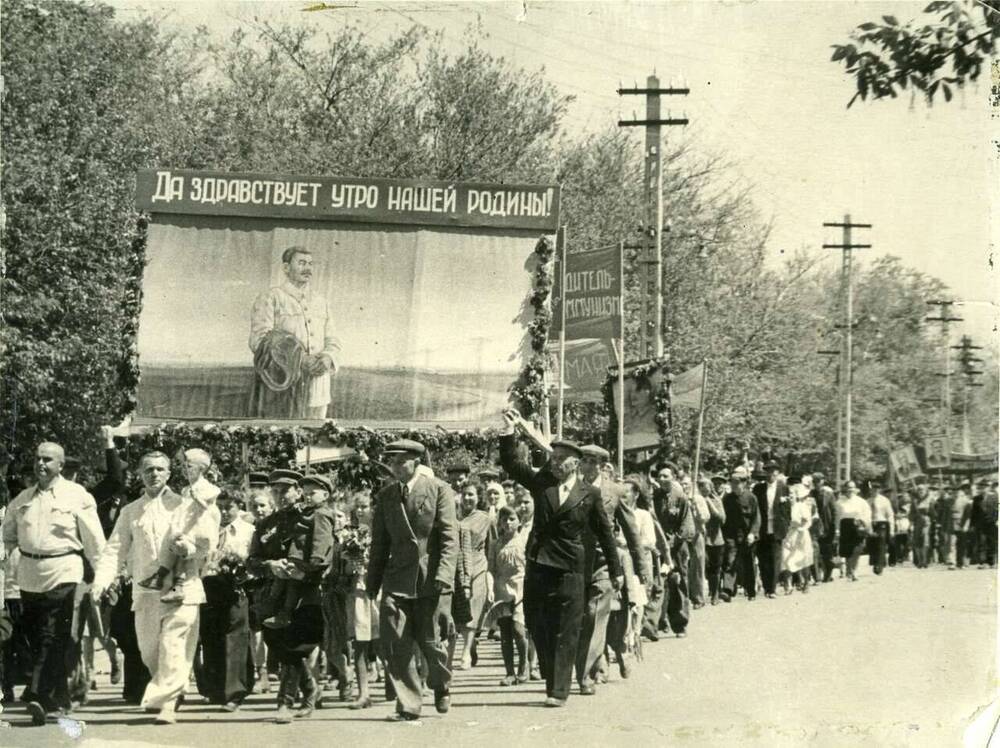 Фотография. Первомайская демонстрация. Колонна с транспарантами, плакатом «Да здравствует утро нашей Родины!» с изображением Сталина на фоне полей. г. Ставрополь, 1951 г.