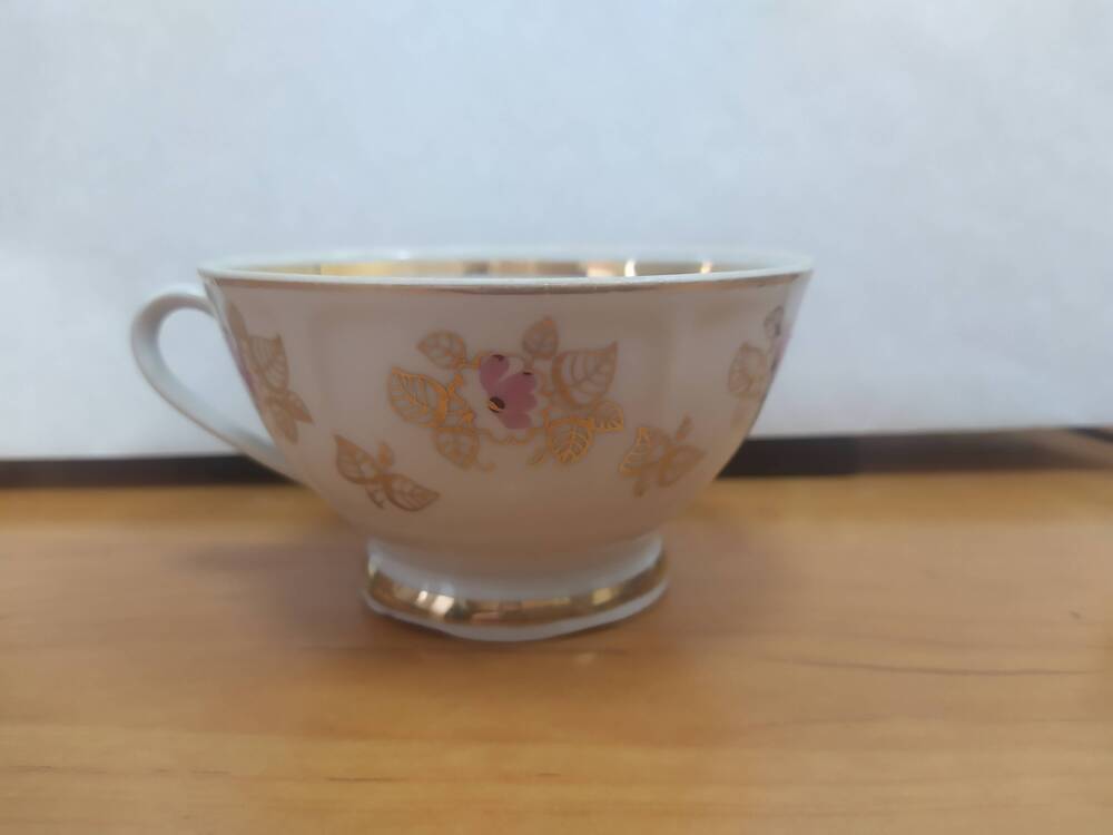 Чашка из сервиза чайного с мелким декором из листьев и розовых цветов.