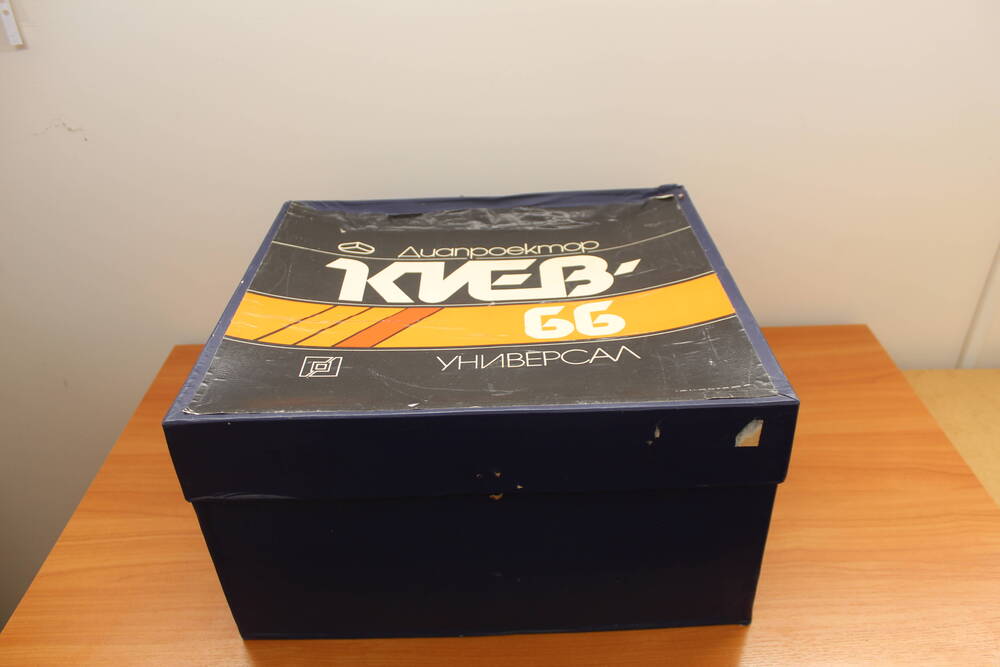 Диапроектор «Киев 66 универсал» в упаковочной коробке.
1. Упаковочная коробка от диапроектора с откидной крышкой темно-синего цвета в центре надпись: «Диапроектор Киев 66 универсал»