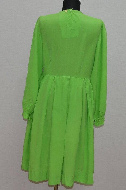 Платье зеленого цвета с длинными  рукавами на манжете, отрезная талия юбка в складку, на горловине волан в виде складок. На спине разрез.  зеленого цвета