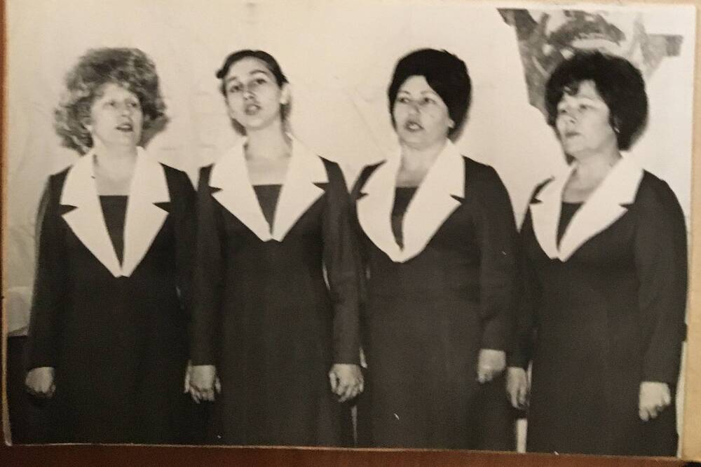 Фото черно-белое, горизонтальное. На снимке в ряд стоят  четыре женщины в темных концертных платьях .