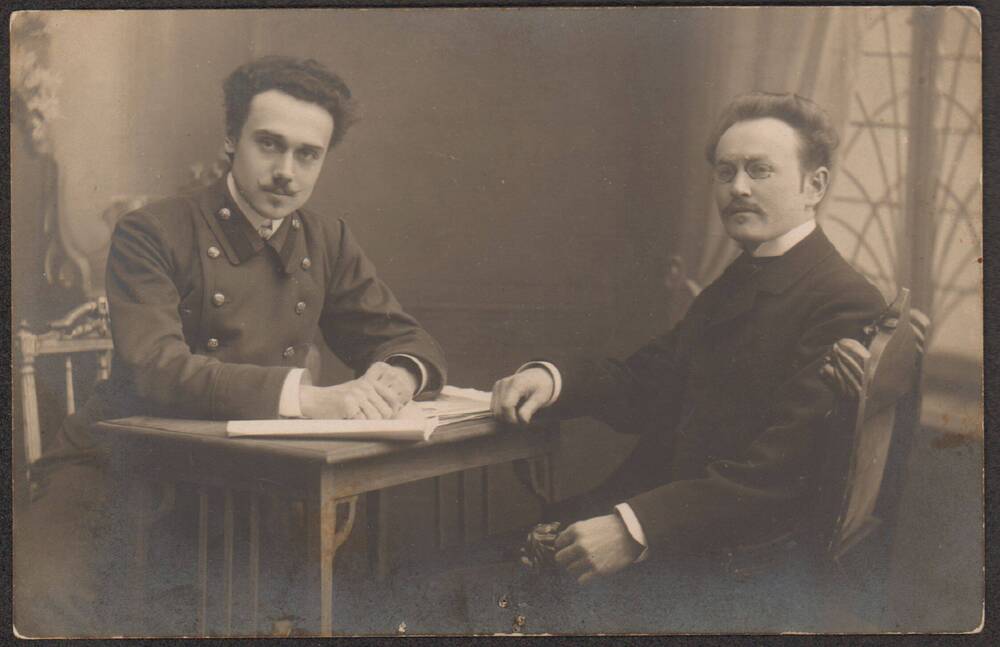 Фотооткрытка. Портрет двух молодых людей за столом (слева Васильев Николай Михайлович)