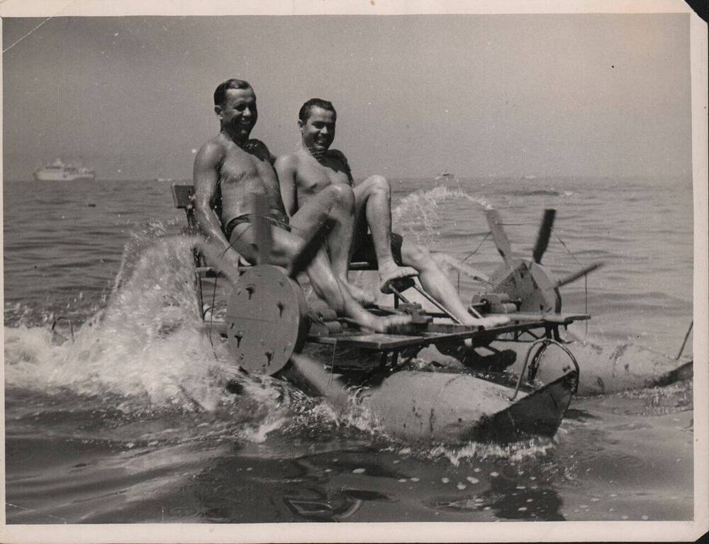 Фото. Летчики – космонавты А. Г. Николаев и П. Р. Попович на водном велосипеде.