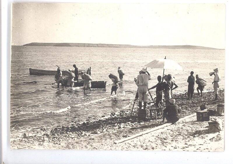 Фотография ч/б. Съемка фильма «Черная пасть» (реж. А.Разумный). Съемочная группа на берегу моря, актеры с тюфяками по колено в воде. 1935 г.