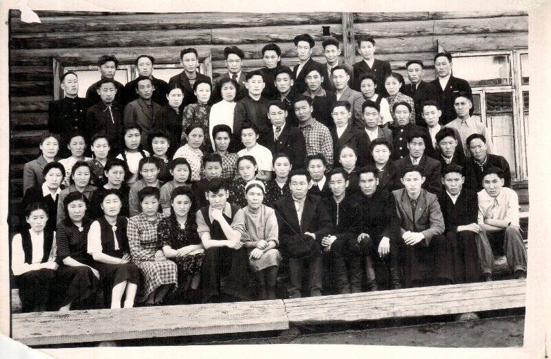 Фотография групповая. Фотография групповая. На снимке изображена группа людей на фоне деревянного здания. Всего 64 человека.