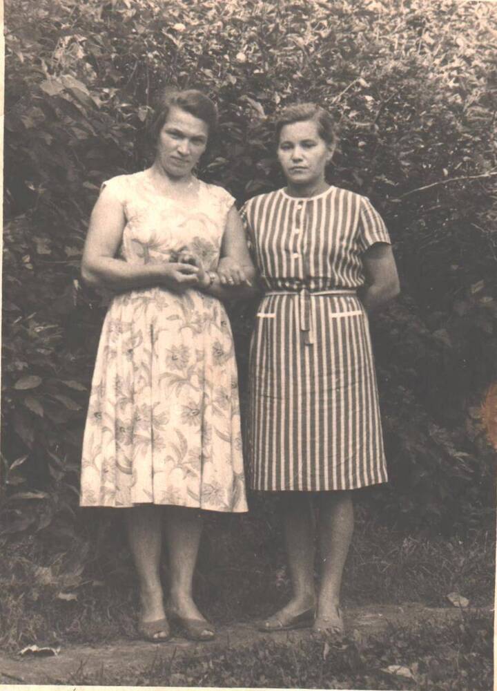 Трут Нина Николаевна(слева) медицинская сестра с подругой стоят у кустарника.