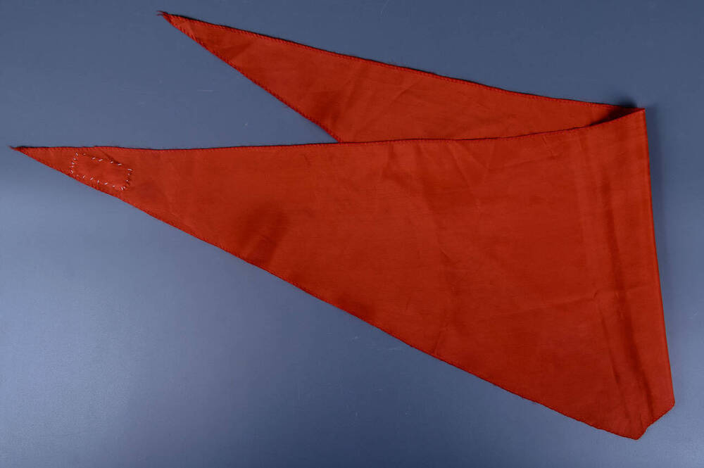 Пионерский галстук красно-оранжевого цвета треугольной формы.
