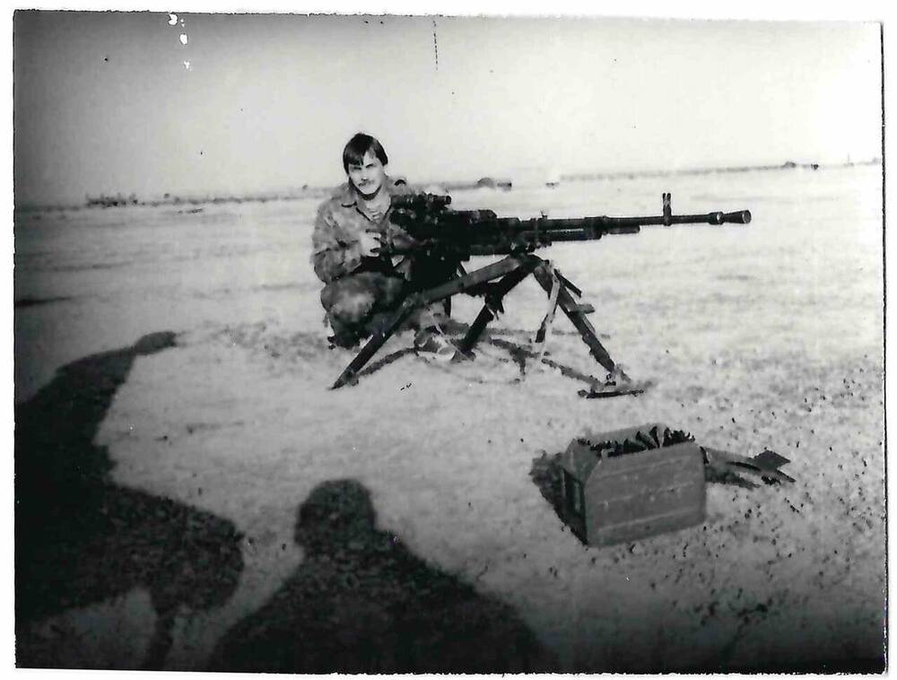 Фотография черно-белая. Изображен сидящий за станковым крупнокалиберным пулеметом Семиболотний С.В. 